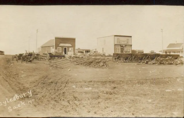 Farm implements and wagons in front of Main Street buildings